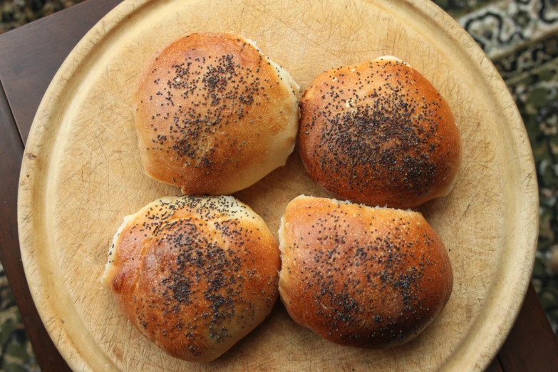 a plate with three brown rolls covered in black sprinkles