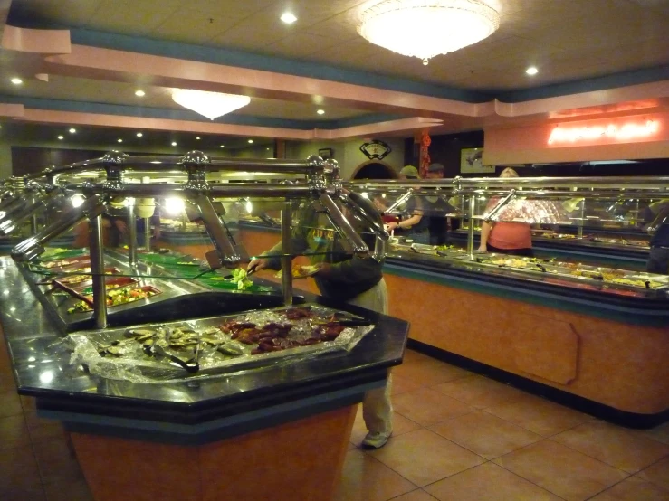 two people stand in front of a buffet line with food on it