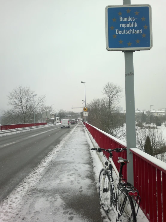 a blue sign saying the route to belgium on a snowy day