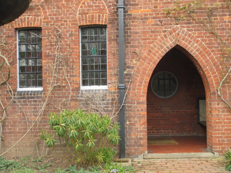 an open door to a brick building near some bushes