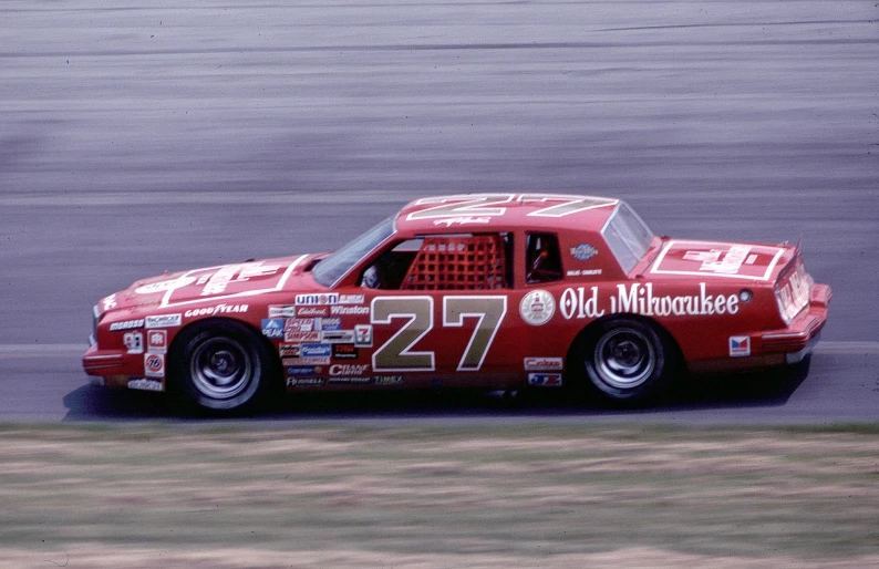 a man in red racing car is turning around on the track