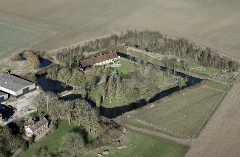 aerial po of house and farm, with large driveway and treed pasture