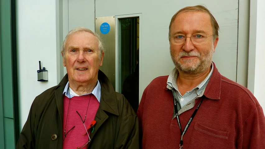 two men are standing next to each other in front of a building