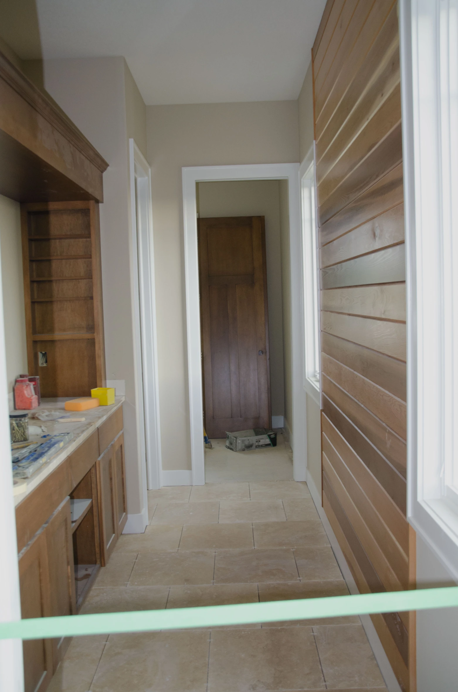 this is a hallway with several wood cabinets and a window