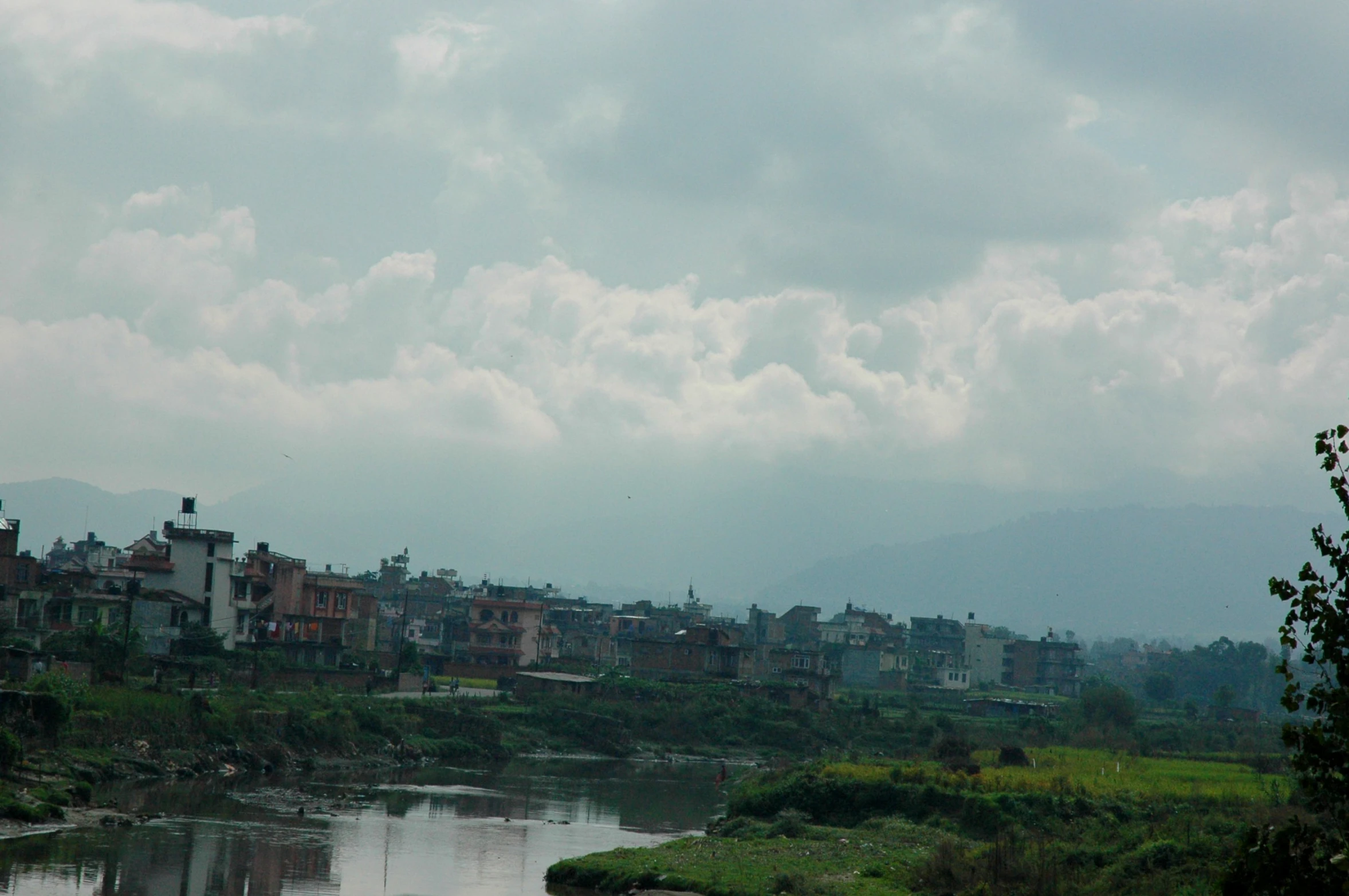 a cloudy sky with some water and lots of buildings on the other side