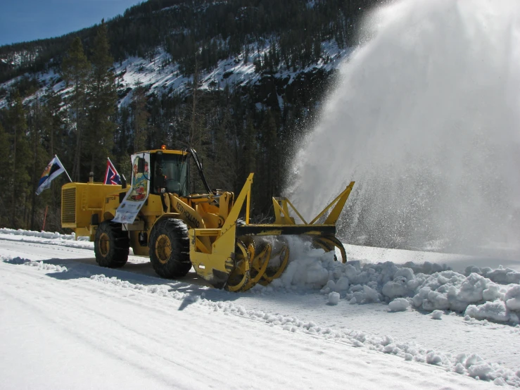 a bulldozer is dumping snow in a road