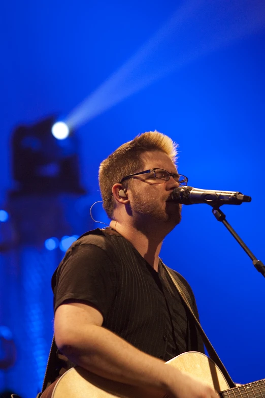 a man playing an acoustic guitar on stage