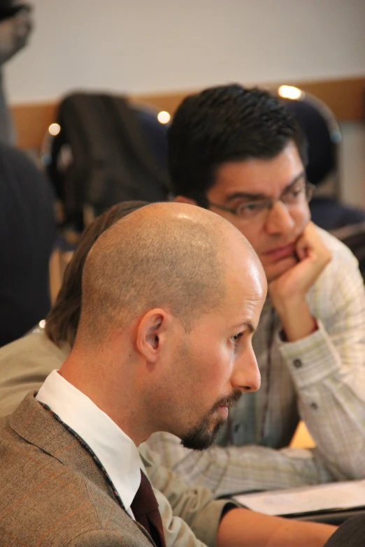 two men sitting at a table with papers and pens