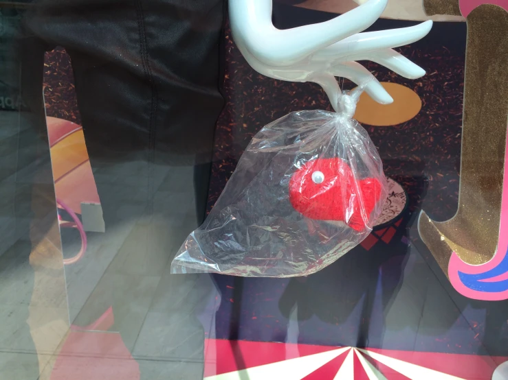 a plastic bag is held up and sits next to some fake hearts