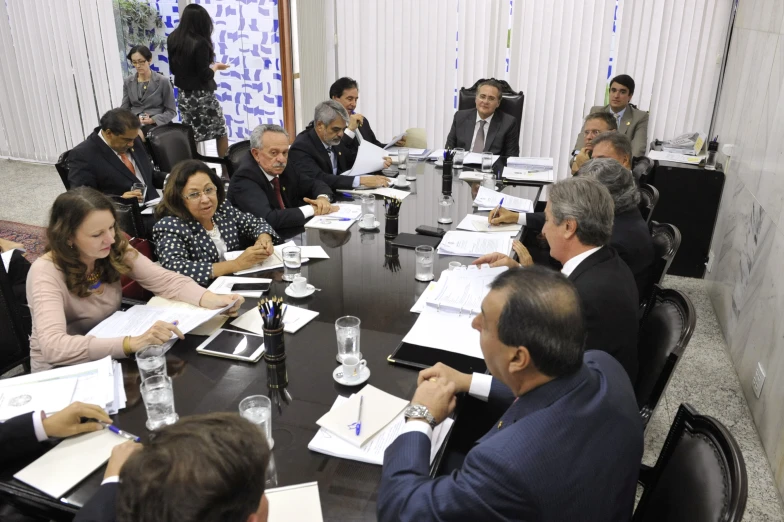 a group of business people sit in front of a long table