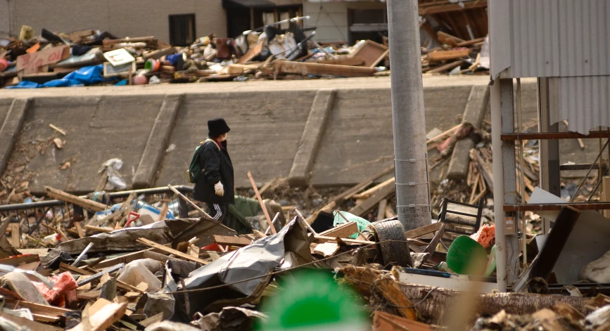 a man in a rubble yard walking away from a pile of wood