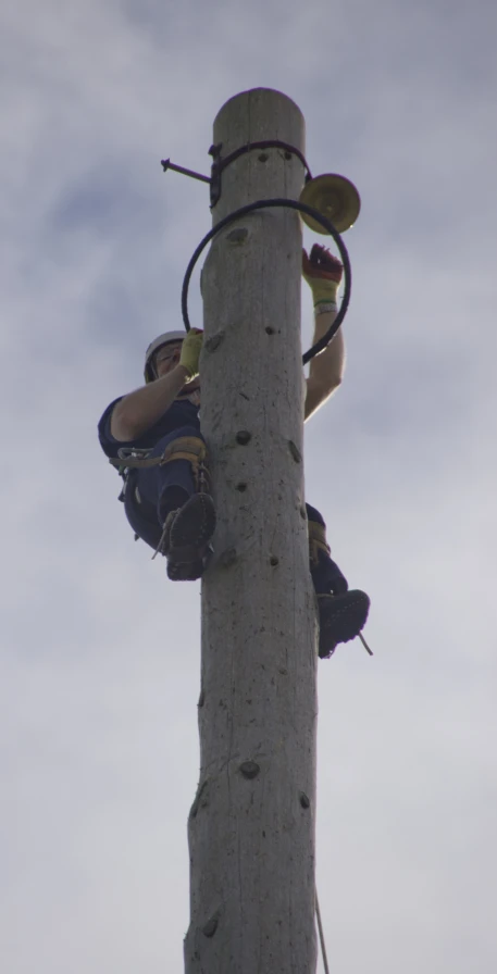 two men climbing up and down a tall pole