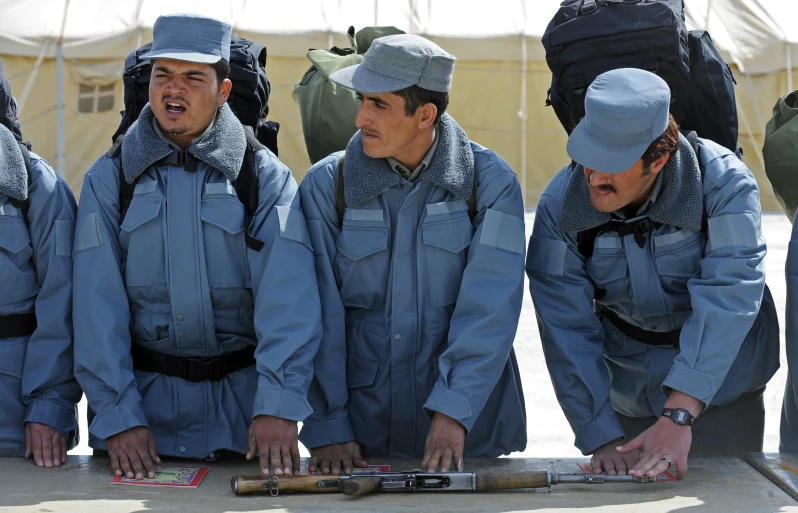 a group of men wearing blue outfits and one holding a gun