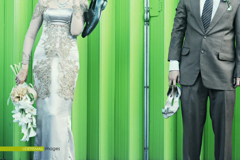 two people in formal wear standing in front of a green wall