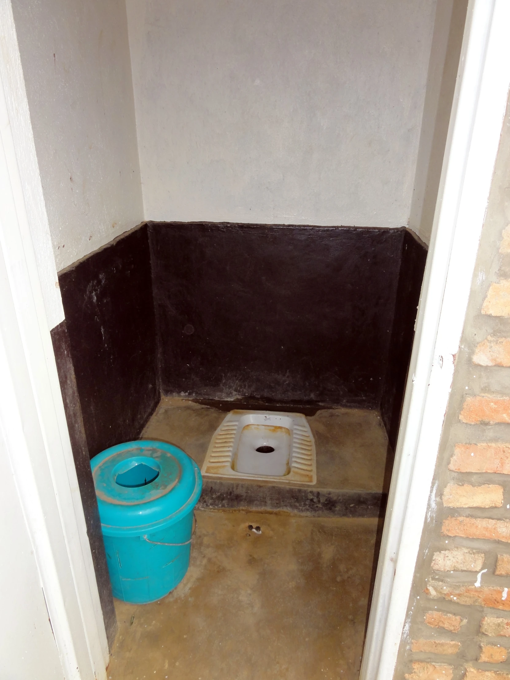 a small room with a blue toilet and brown walls