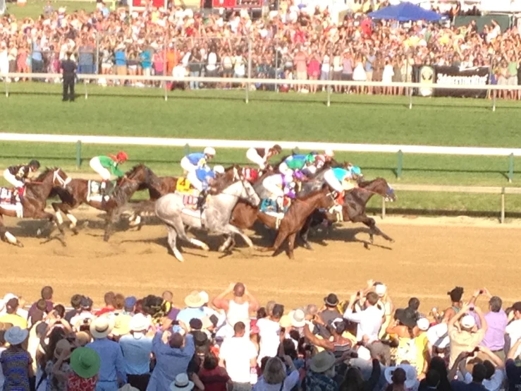 jockeys racing horses at a track with spectators