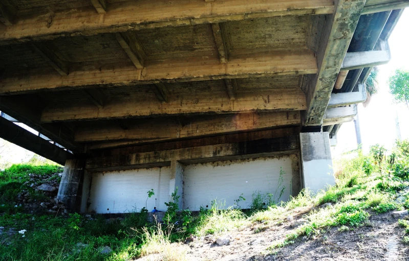 an old bridge in the country with weeds and grass