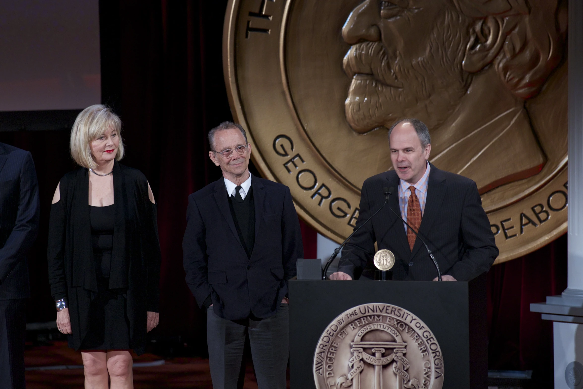 three people standing at podium in front of president kennedy presidential seal