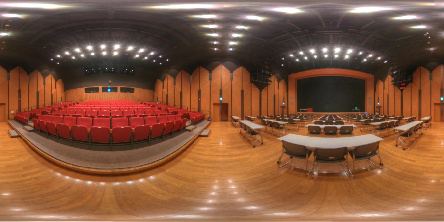 an empty auditorium with red seats and a projector screen