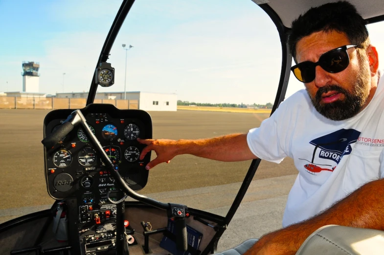 a man in sunglasses operating a small airplane cockpit