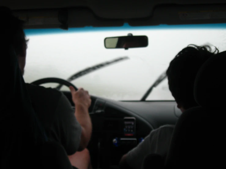 a view of two people driving through the windshield