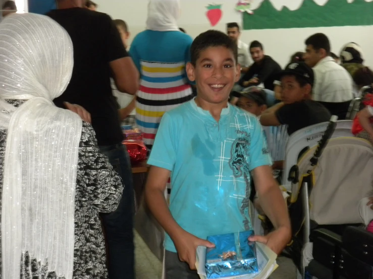 a boy in blue shirt holding a cake at a party