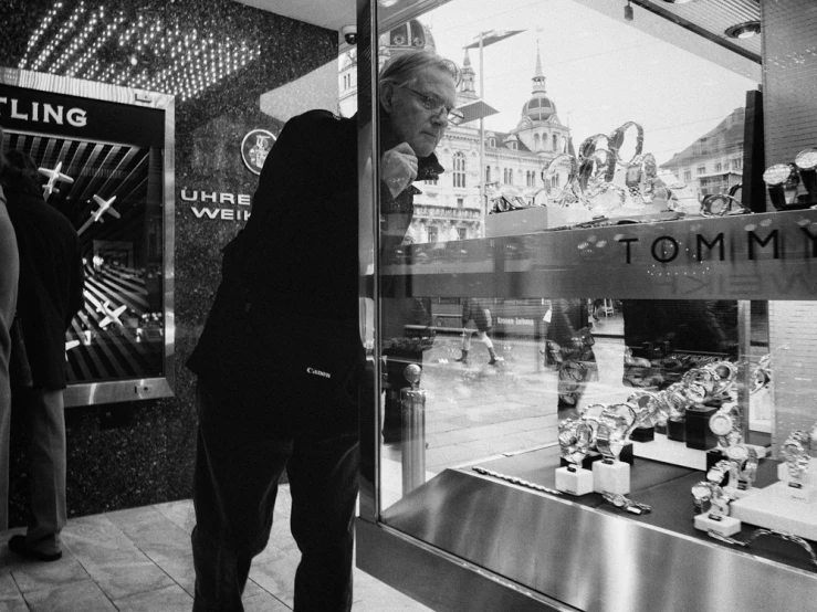 a man is leaning against the glass in front of a shop