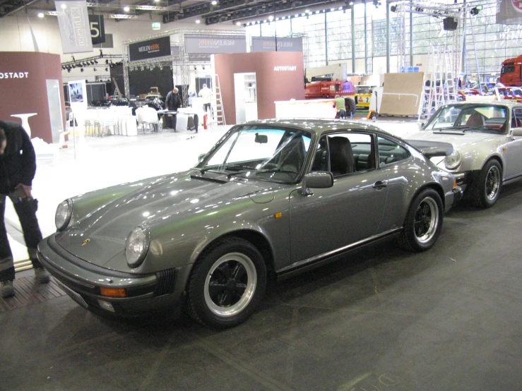 a group of men viewing a gray car in a showroom