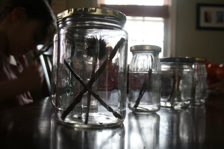 woman sitting at a table with jars and spoons