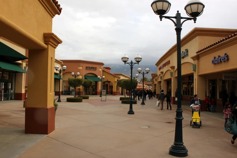 a street light next to a walkway and some people walking down the sidewalk