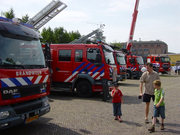 a group of children standing in front of a row of fire trucks