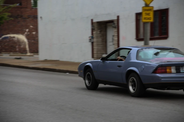 a silver sports car with a person driving on the road