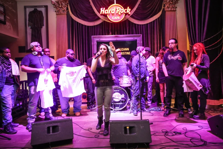 a woman standing on a stage with microphone and a band behind her