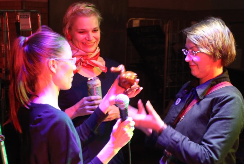 a group of three women talking and holding soing