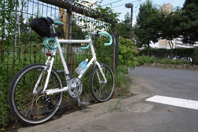 a white bike sitting up against a chain linked fence