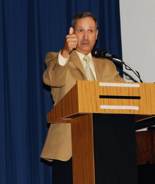 a man giving a thumbs up during a podium presentation