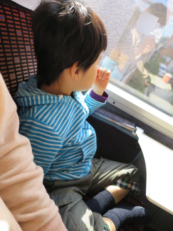 small boy sitting inside of seat looking out window