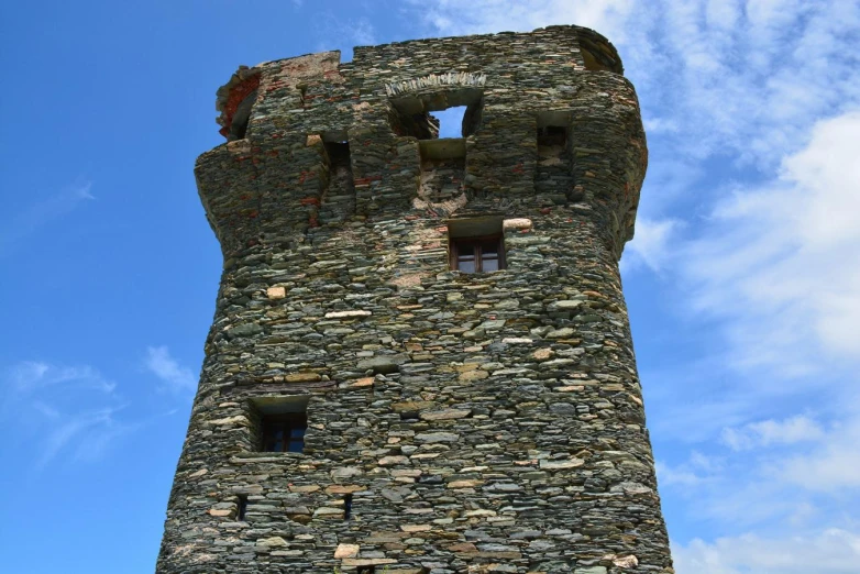 a stone clock tower has small windows and brick walls