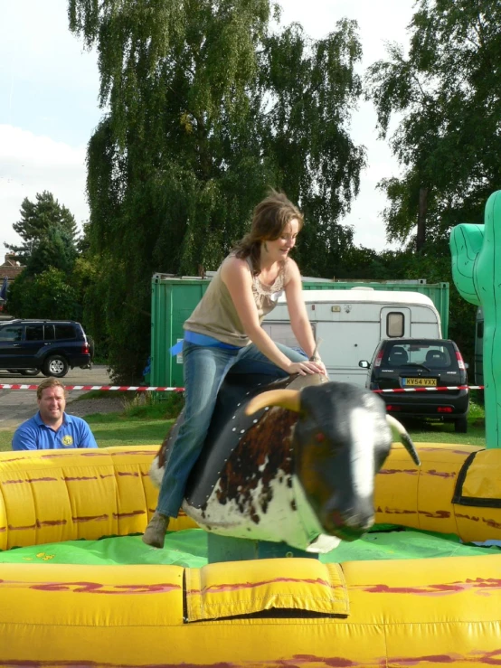 a woman with a cow that is jumping over an obstacle