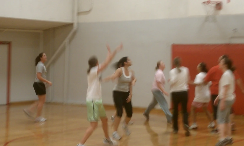 women playing basketball inside of a gym while other people watch