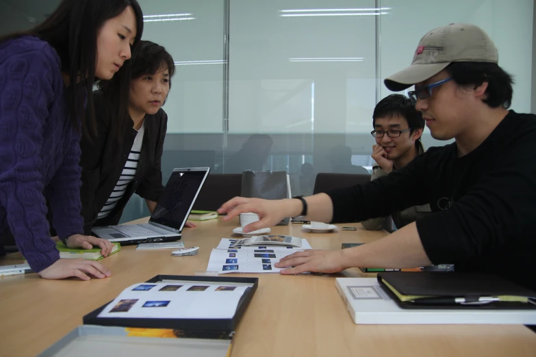 three people in front of two computers at a table