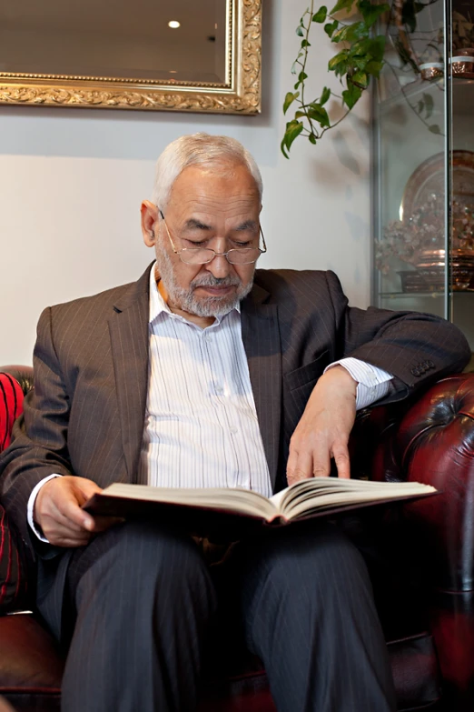 an older man in a suit is looking at the book