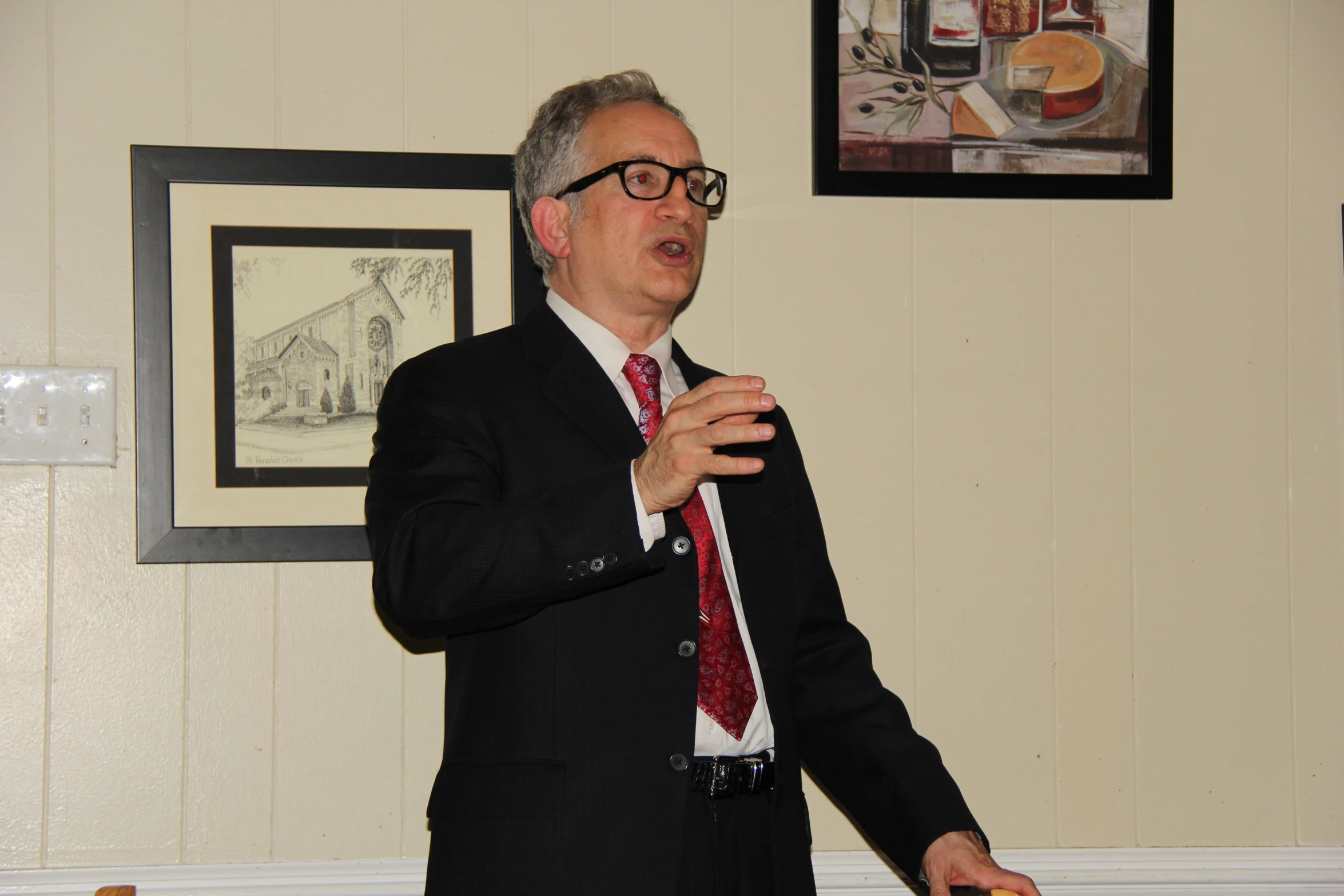 a man standing in front of a white table and giving a presentation