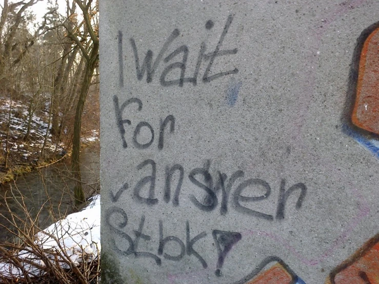 graffiti on concrete beside a river reads wait for hanssen blocky