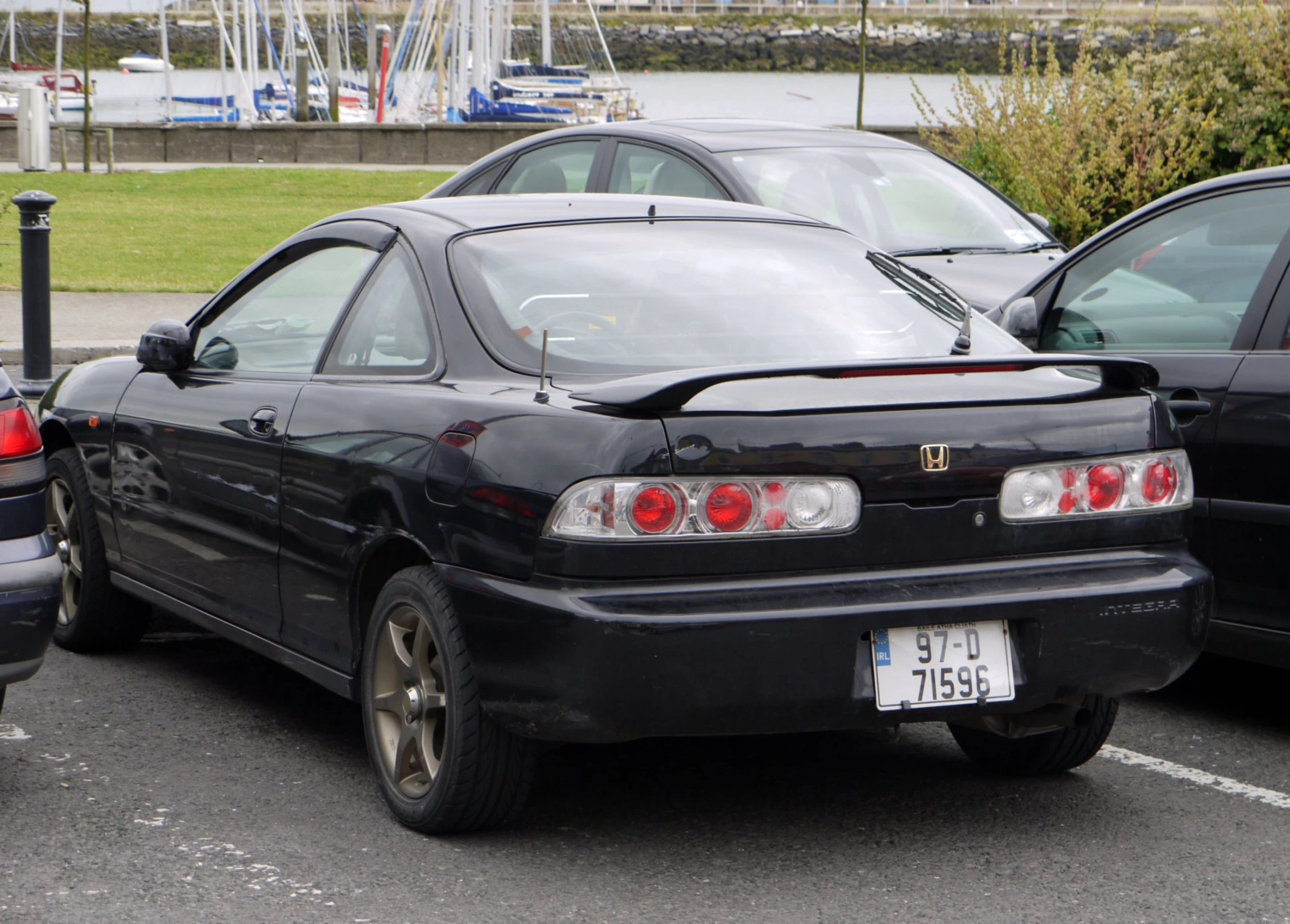 a black car sitting in a parking lot next to another car