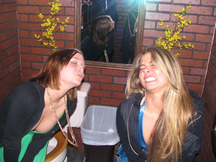 two woman taking a picture in the mirror of a bathroom