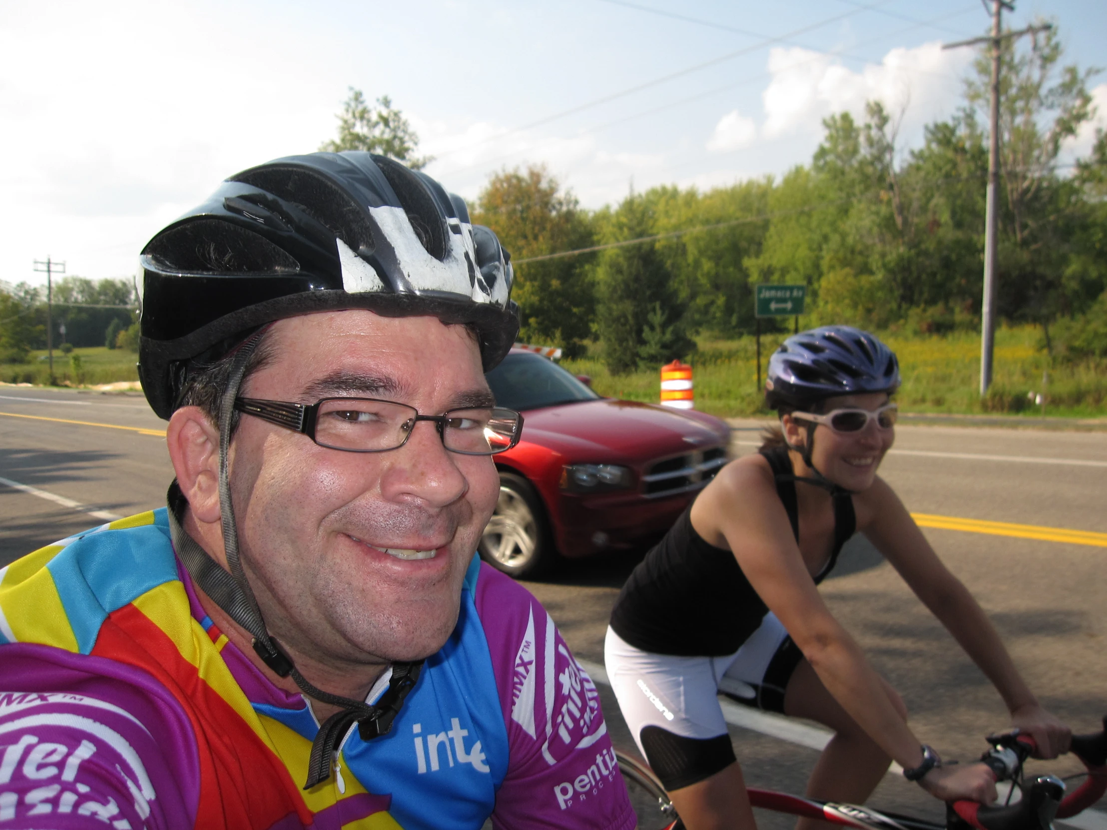 a man on a bicycle smiles while another person is behind him