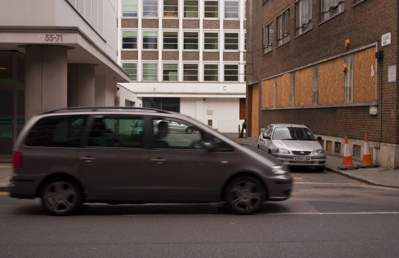 a car driving down a street next to a tall building