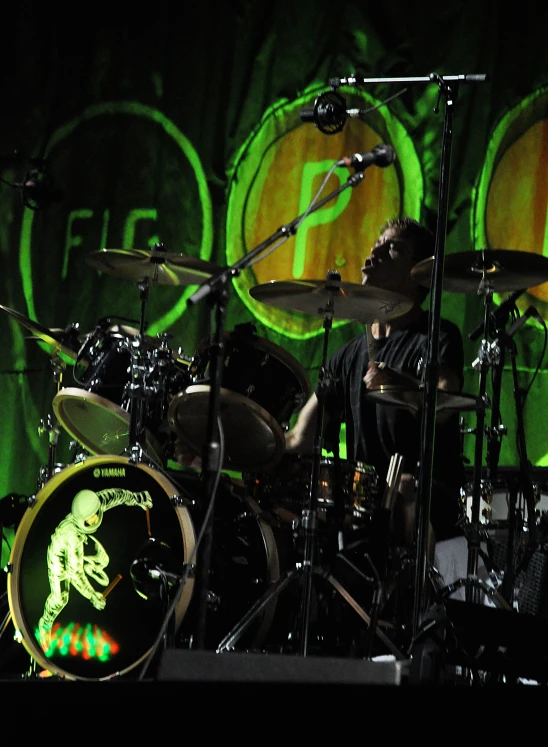 a drum player on stage, with a picture behind him