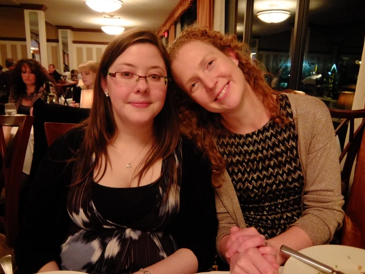 two women sitting at a restaurant table with a plate of food in front of them